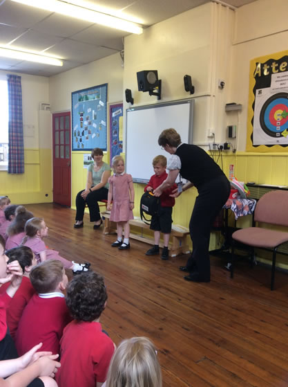 Kay Reeve [right] presenting the defibrillator to pupils and staff of Terrington St John's Junior School