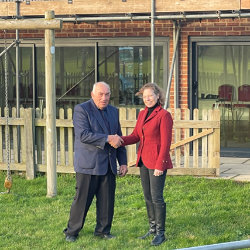 George Brett-Reynolds welcomes Susan Falch-Lovesey to Wighton Village Hall.